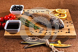 Fresh dorado grill with lemon and cherry tomatoes on a wooden tray. For restaurant menu or recipe