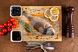 Fresh dorado grill with lemon and cherry tomatoes on a wooden tray. For restaurant menu or recipe