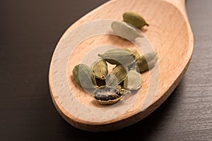 Fresh dried cardamom cardamon seeds spice on a wooden spoon
