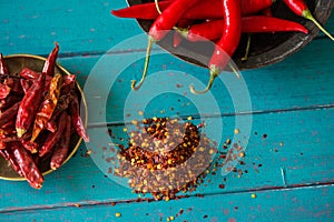 Fresh and dried hot chilli in bowl and seeds on table