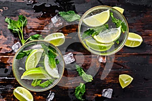 Fresh drink lemonade mojito. Mojitos with mint leaves, lime and ice. Black wooden background. Top view