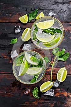 Fresh drink lemonade mojito. Mojitos with mint leaves, lime and ice. Black wooden background. Top view