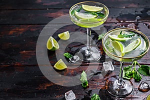 Fresh drink lemonade mojito. Mojitos with mint leaves, lime and ice. Black wooden background. Top view. Copy space