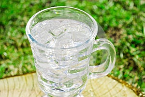 Fresh drink water with ice in glass on nature background