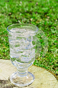 Fresh drink water with ice in glass on nature background