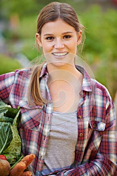 Fresh from the earth. Portrait of a happy young woman holding a crate full of freshly picked vegetables.