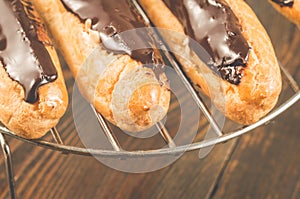 Fresh eclairs on a metal support/fresh eclairs on a metal support on a wooden background. Top view