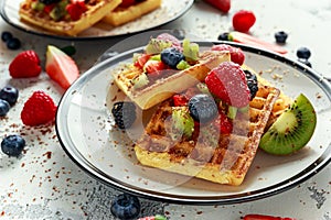 Fresh egg waffles dessert for breakfast with fruits strawberries, blueberries, blackberries, raspberries and kiwi