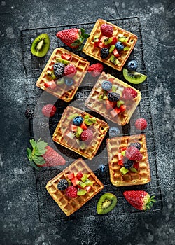 Fresh egg waffles dessert for breakfast with fruits strawberries, blueberries, blackberries, raspberries and kiwi