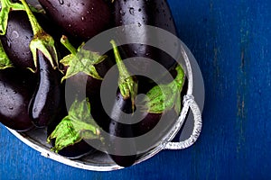 Fresh eggplant in grey basket on blue wooden table.Rustic background. Top view. Copy space. Vegan vegetable.