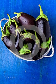 Fresh eggplant in grey basket on blue wooden table.Rustic background. Top view. Copy space. Vegan vegetable.