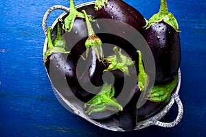 Fresh eggplant in grey basket on blue wooden table.Rustic background. Top view. Copy space. Vegan vegetable.