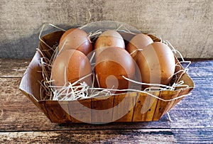 Fresh eggs in a basket on wooden table