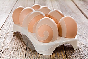Fresh eggs in an egg tray on a wooden table