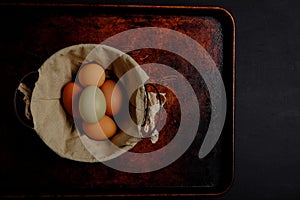 Fresh eggs, green and brown, wire basket, on dark background