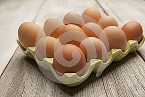 Fresh eggs in a green ceramic holder on rustic background