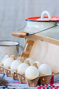 Fresh eggs in a paper container and milk in a can on a wooden ba