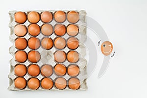 Fresh eggs in paper tray with one smiling egg out of tray on white background