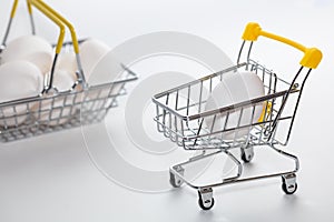 Fresh eggs in a shopping cart and a part of basket blurred in the background. Shopping, purchasing, and food delivery concept
