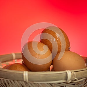 Fresh eggs with water condensation in a rattan basket. Isolated on Red background. Shallow depth of field