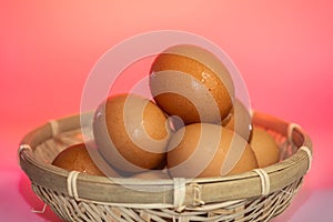 Fresh eggs with water condensation in a rattan basket. Isolated on Red background. Shallow depth of field