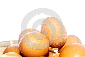 Fresh eggs with water condensation in a rattan basket. Isolated on white. Shallow depth of field