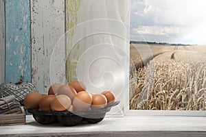 Fresh eggs on window sill, grain field in background