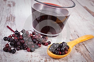 Fresh elderberry with wooden spoon and juice on old wooden background, healthy nutrition