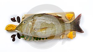 Fresh Emperor Fish decorated with herbs and vegetables on a wooden pad.White Background