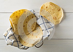 Fresh, empty wheat tortilla flat lay top view on dishcloth on white wooden table