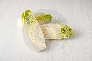 Fresh Endive or Chicory Cichorium endivia whole and halved on a white wooden table, copy space