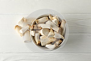 Fresh eringi mushrooms in bowl on white wood background