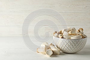 Fresh eringi mushrooms in bowl on white wood background