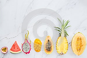 Fresh exotic fruits and tropical palm leaves on white marble background - papaya, mango, pineapple, passion fruit