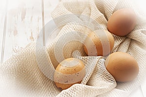 Fresh farm brown eggs over a beige rustic napkin and shabby white wooden table