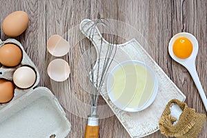 Fresh farm eggs on a wooden rustic background. Separated egg white and yolks, broken egg shells.