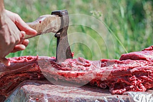 Fresh farm sheep carcase chopping by axe in man hand