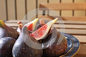 Fresh figs on ceramic black plate Wooden table Sunligh Copy space Autumn harvesting F photo