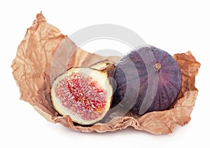 Fresh figs. Fruit and a half on craft wrapping paper isolated on white background. With clipping path.