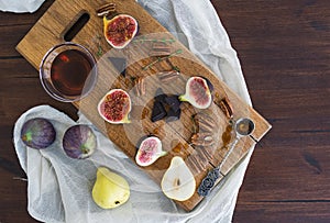 Fresh figs, pears and pekan nuts with honey on a wooden board photo