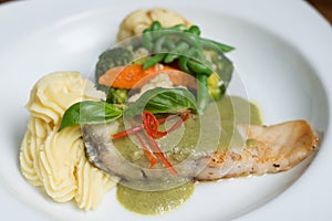 Fresh fillet of sea bass pan fried in lemon caper sauce served with mashed potatoes and green vegetables