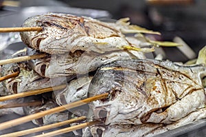 Fresh fish baked on a grill on wooden skewers looks appetizing photo