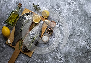 Fresh fish dorado or sea bass on cutting board with ingredients