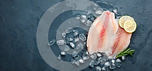 Fresh fish fillet of sea bass in ice on a dark slate background.