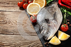 Fresh fish, lemon, spices and cherry tomatoes on a stone board