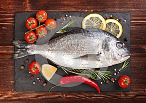 Fresh fish, lemon, spices and tomatoes on a board