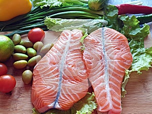 Fresh Fish Raw Salmon Two steaks with ingredients vegetables and spices tomatoes lemon and olives cucumber green salat onion g