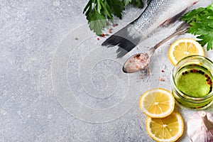 Fresh fish. Sea Bass raw with salt, pepper, parsley, olive oil and lemon on cutting board on light gray concrete rustic background