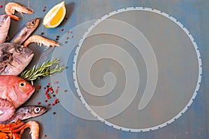 Fresh fish, seafood, octopus and lemon on a blue wooden background with copy space.