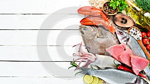 Fresh fish and seafood on a white wooden background. Flounder, lobster, squid, tuna, fish.